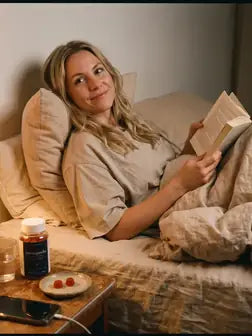 Frau liest abends im Bett, Dose auf dem Nachttisch