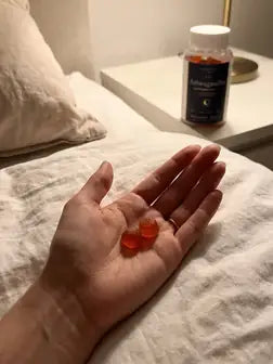Zwei Gummibärchen in der Hand, Dose am Bett
